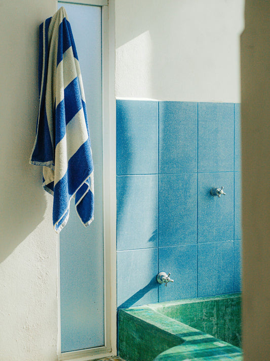 Green bathtub with Blue & White Stripe towel hanging up